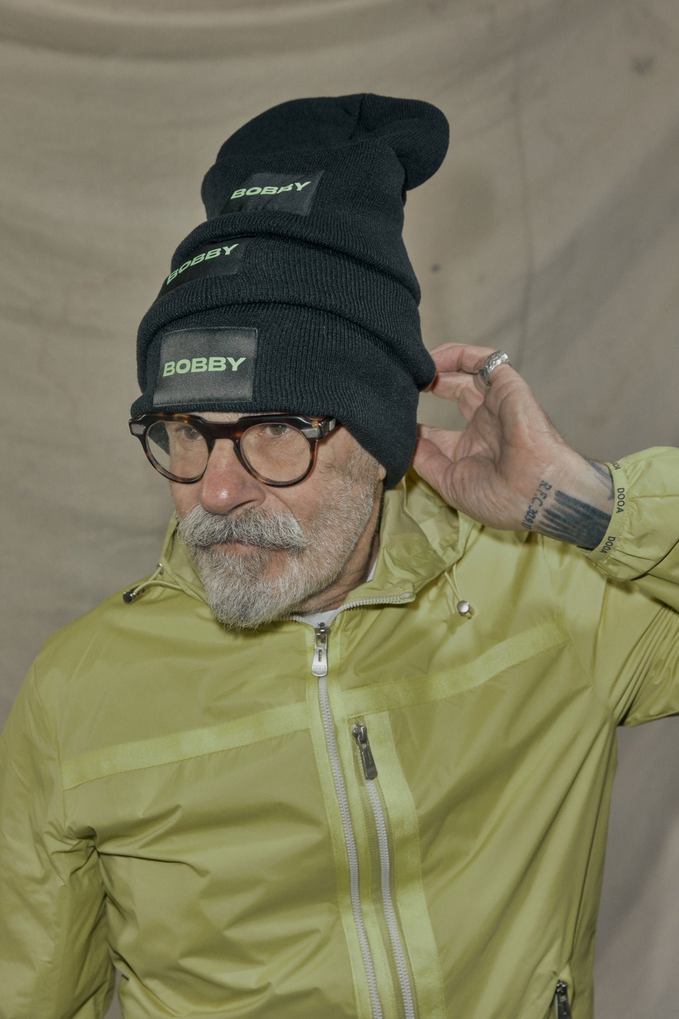 silver fox man wearing a stack of three beanies from bobbys winter merch capsule