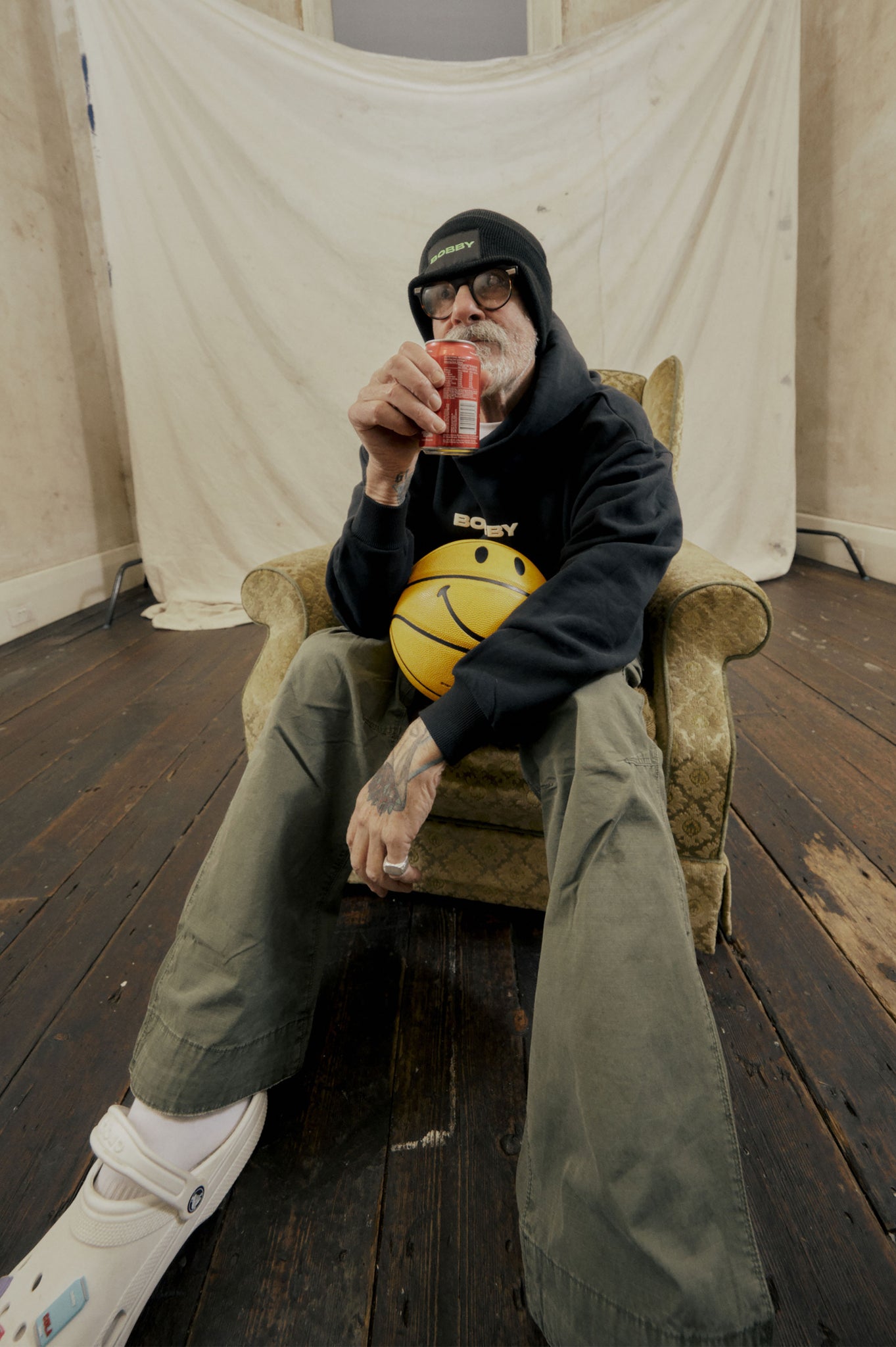 wide angle shot of man posing and drinking a cold bobby beverage in a studio