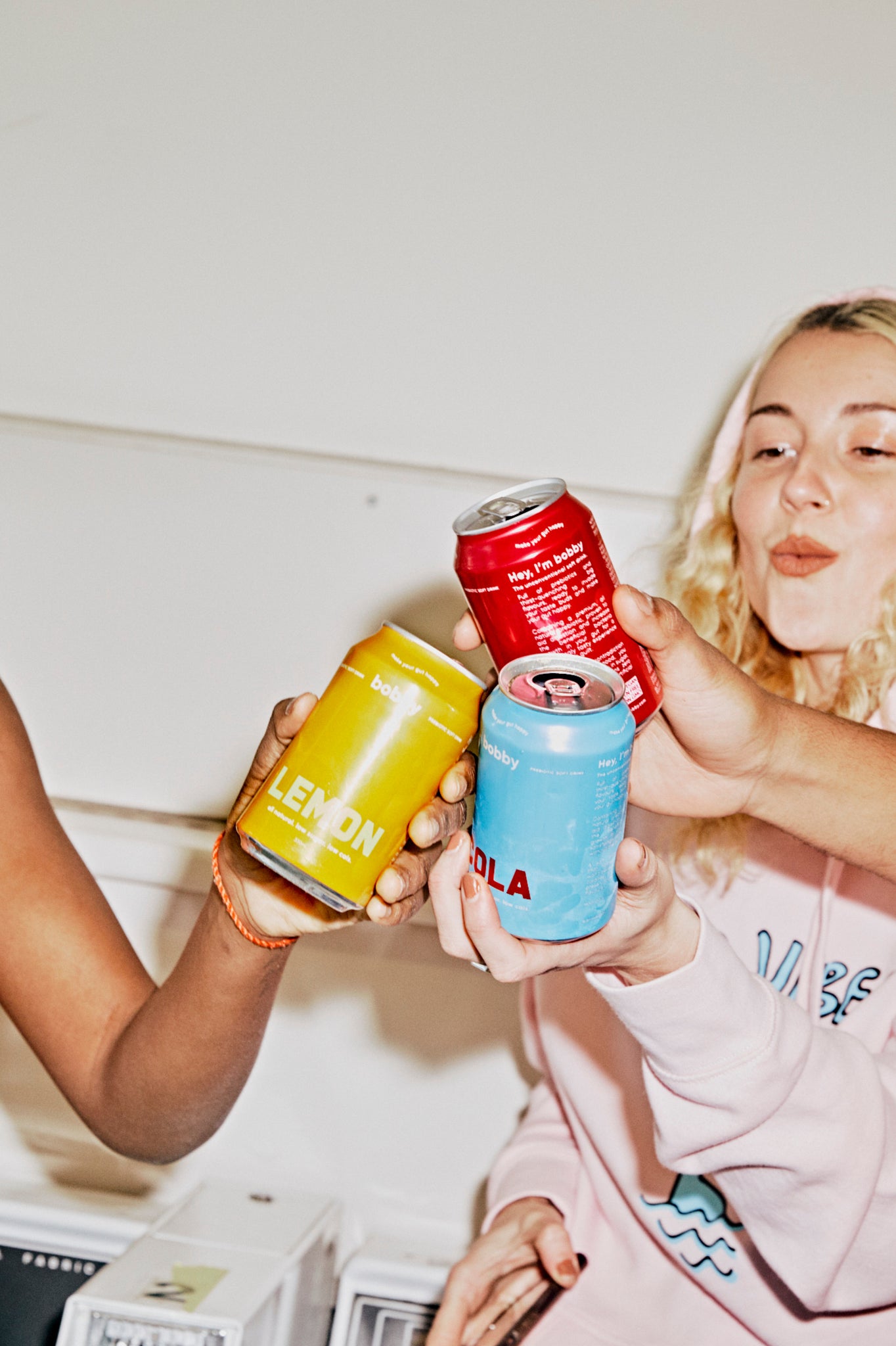 three best friends sharing cans of cola, lemon and berry bobby soft drinks