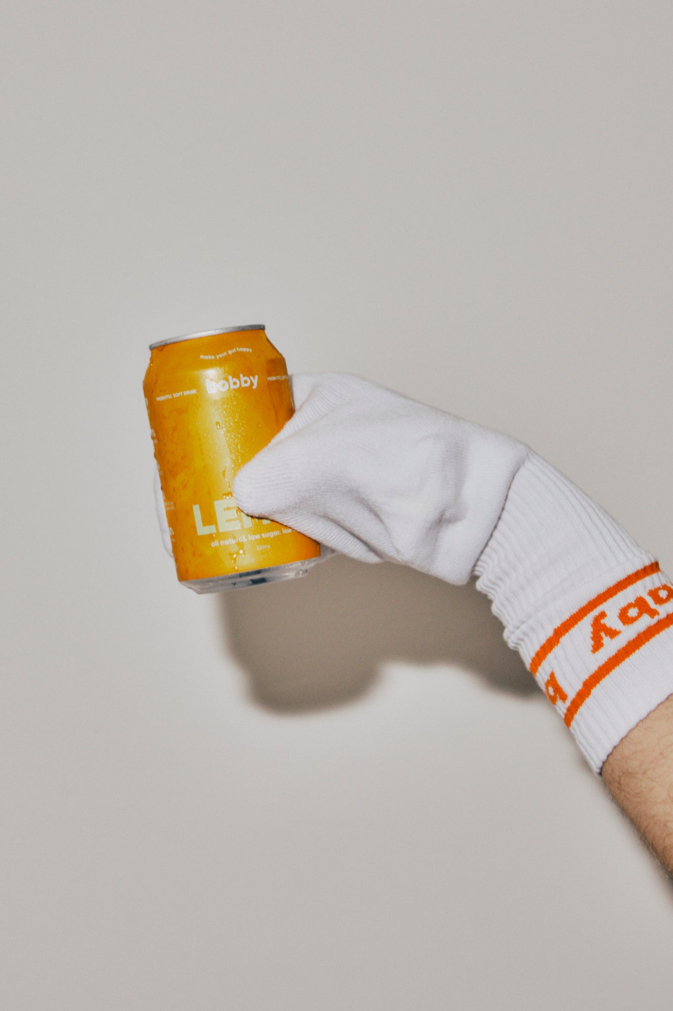 bobby branded socks with orange details on a hand, hand holding can of cold lemon bobby